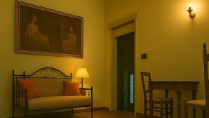 A room with a sofa, a dining table with chairs, a red rug, and a painting on the wall. - Florence center apartment in former convent (Firenze)