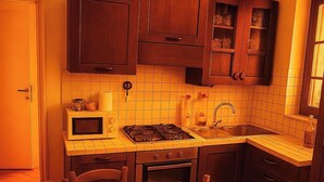 A compact kitchen with a stove, microwave, and sink. There is a dining table with chairs and a window providing natural light. - Florence center apartment in former convent (Firenze)
