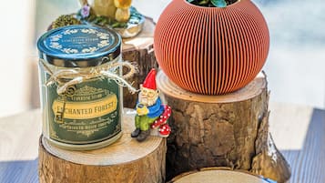 A rustic wooden table with a decorative gnome figurine, a potted plant, a tin can, and a round wooden coaster.