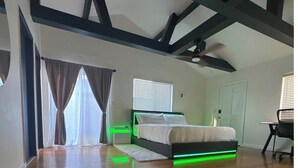 A bedroom with a bed, a desk, and a ceiling fan.