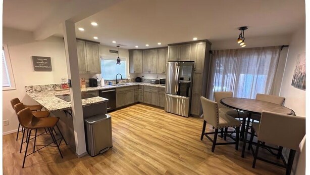 A modern kitchen with a central island, built-in appliances, and a dining area with chairs.
