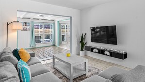 Ein modernes Wohnzimmer mit einem grauen Sofa, einem Couchtisch und einem an der Wand montierten Fernseher.