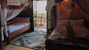 Una habitación rústica y acogedora con dos camas, una con dosel y la otra con cabecera. Se observa un suelo de madera y una alfombra estampada.