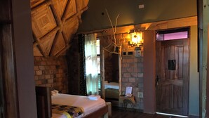 Una habitación acogedora con una cama, un banco de madera, un tapiz de cuadros y una pared de piedra.