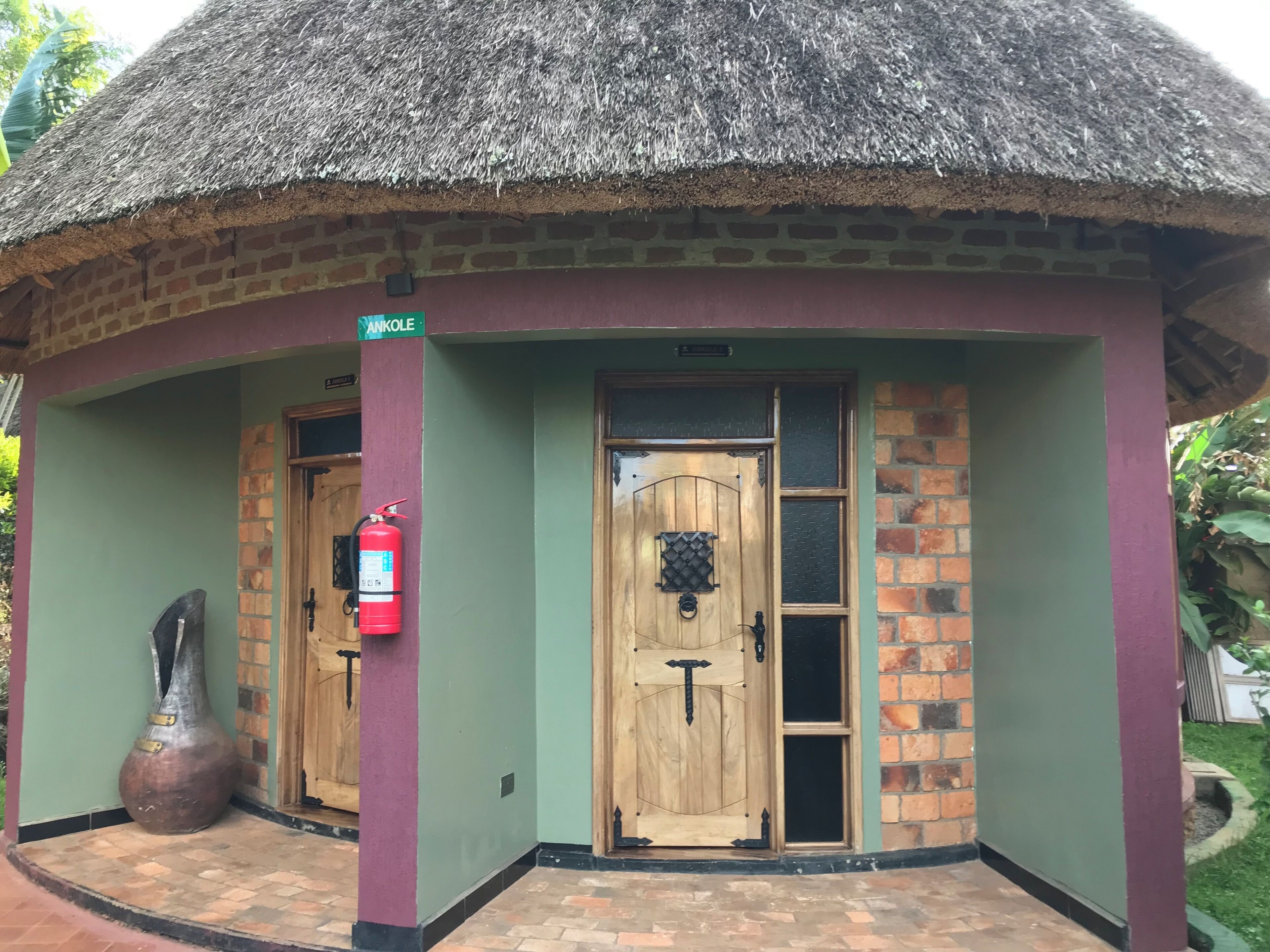 A building with a thatched roof, two wooden doors, and a fire extinguisher mounted on the wall.