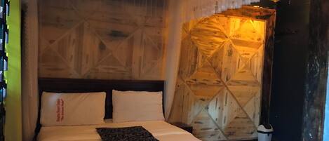 Una cama con ropa blanca y un corredor estampado, cabecera de madera y pared con diseño geométrico.