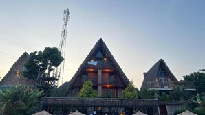 Un edificio de techo triangular con un balcón y una estructura de techo de paja al frente.