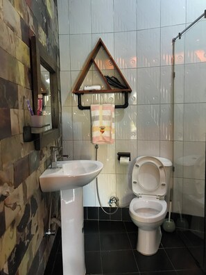 Une salle de bain avec un lavabo blanc, des toilettes et un porte-serviettes sur lequel est accrochée une serviette.