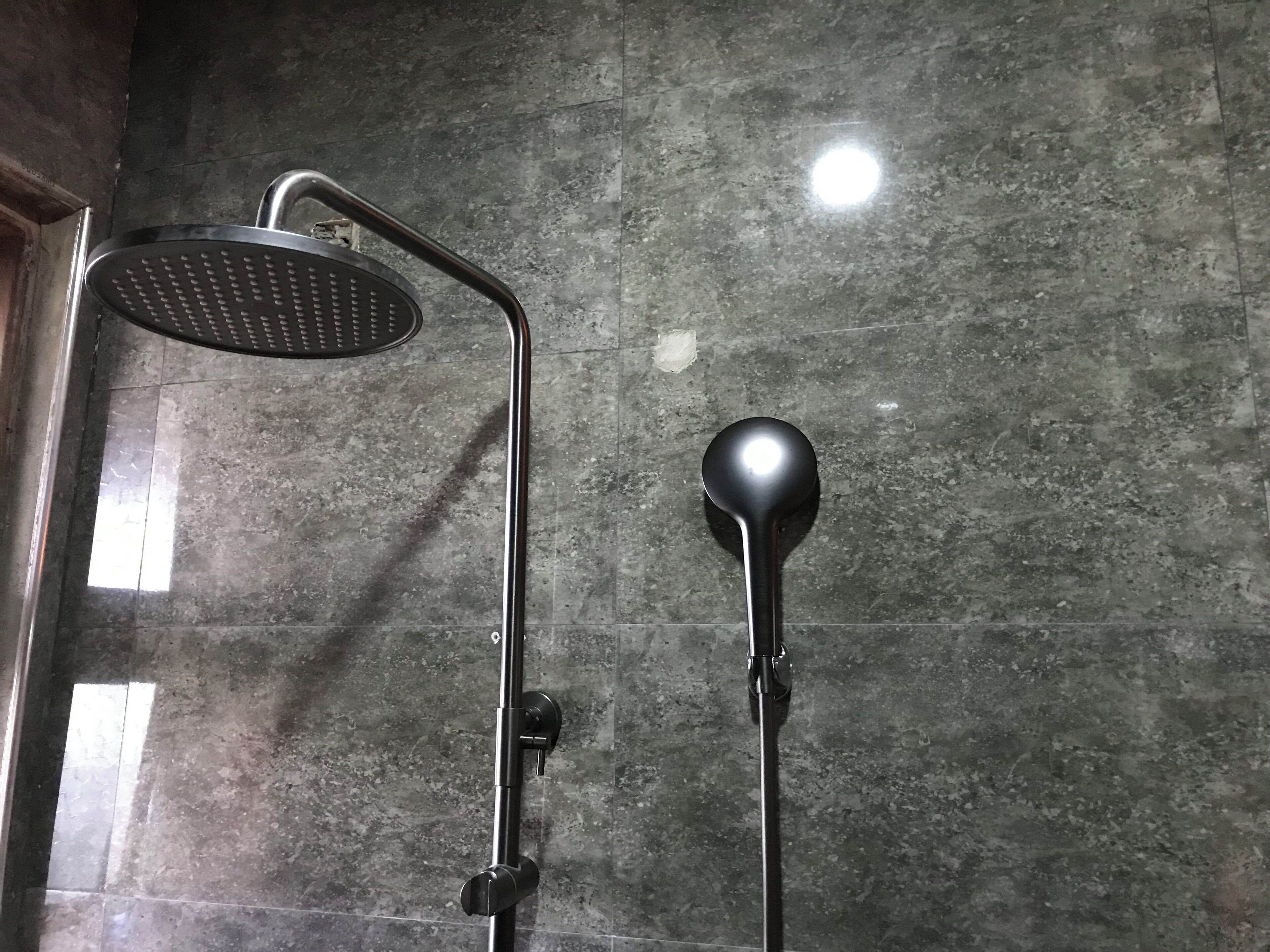A shower with a handheld showerhead and a fixed wall-mounted showerhead.