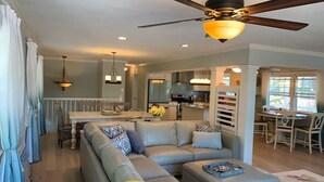A modern living room with a sectional sofa, a dining area, and a kitchen.