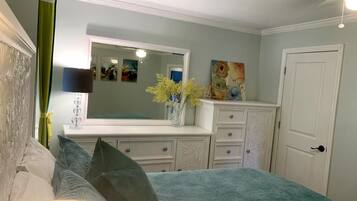 Un dormitorio con cama, cómoda, espejo y cuadros en la pared.