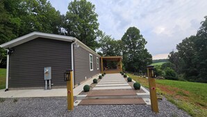 A house with a covered porch, a small deck, and a gravel pathway leading to the entrance.