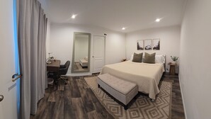 A bedroom with a bed, a desk, a chair, a bench, and a door.