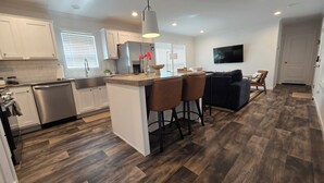 A modern kitchen with white cabinets, a stainless steel refrigerator, and a wooden island with bar stools.