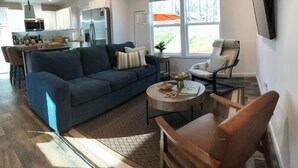 A modern living room with a blue sofa, a round coffee table, and a wooden chair.