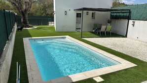 A rectangular swimming pool with a tiled edge, surrounded by artificial grass and a gravel area. - House with swimming pool in Provence near la sainte victoire (Fuveau)
