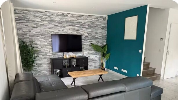 A modern living room with a sectional sofa, a flat-screen TV, a wooden coffee table, and a stone-textured wall. - House with swimming pool in Provence near la sainte victoire (Fuveau)
