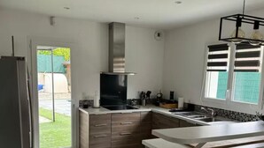 A modern kitchen with a built-in stove, a large island, and a window with blinds. - House with swimming pool in Provence near la sainte victoire (Fuveau)