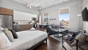 Un appartement moderne comprenant une cuisine, un coin repas et un salon. Il est équipé d’un grand lit, d’un canapé et d’une télévision.