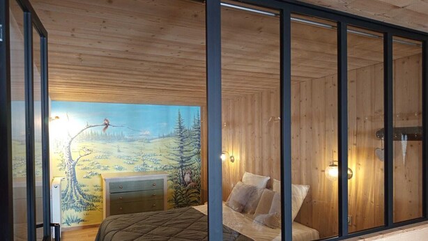Ein Schlafzimmer mit einem Bett, einem Schminktisch und einer Wandmalerei von Waldszenerie.