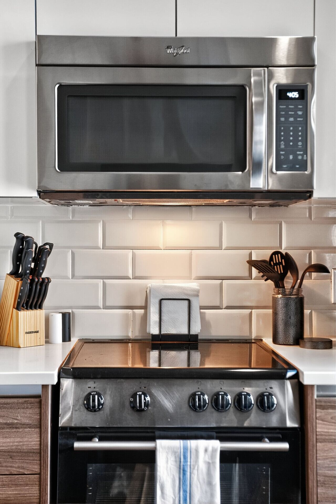Una cocina con un microondas de acero inoxidable, un tostador y una estufa con cuatro hornillas.