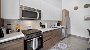 A modern kitchen with white cabinetry, stainless steel appliances, a built-in oven, and a microwave. - Modern Downtown 2BR | Pool, Laundry, Valet Parking (Dallas)