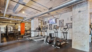 A gym with treadmills, elliptical machines, and weightlifting equipment. - Walk to Convention Center | Pool + Valet Parking (Dallas)