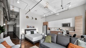 A modern hotel room with a bed, sofa, and kitchenette. - Walk to Convention Center | Pool + Valet Parking (Dallas)