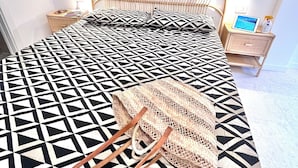 A bed with a geometric patterned bedspread, a woven bag, and a tablet on a bedside table. - Bay of Saracens, renovated apartment 6 people with garden parking space (Varigotti)