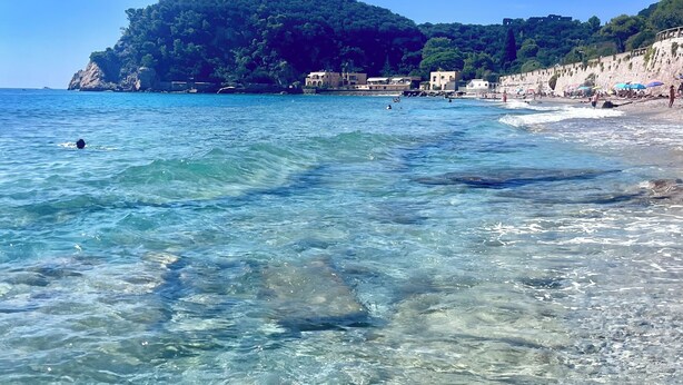 A beach with clear water, a rocky outcrop, and buildings in the background. - Bay of Saracens, renovated apartment 6 people with garden parking space (Varigotti)