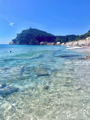A beach with clear water, a rocky outcrop, and buildings in the background. - Bay of Saracens, renovated apartment 6 people with garden parking space (Varigotti)