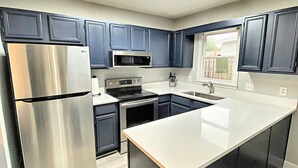 A modern kitchen with dark blue cabinets, stainless steel appliances, and a large island. - Charming Coastal Cottage Near Beach & Downtown (Wilmington)