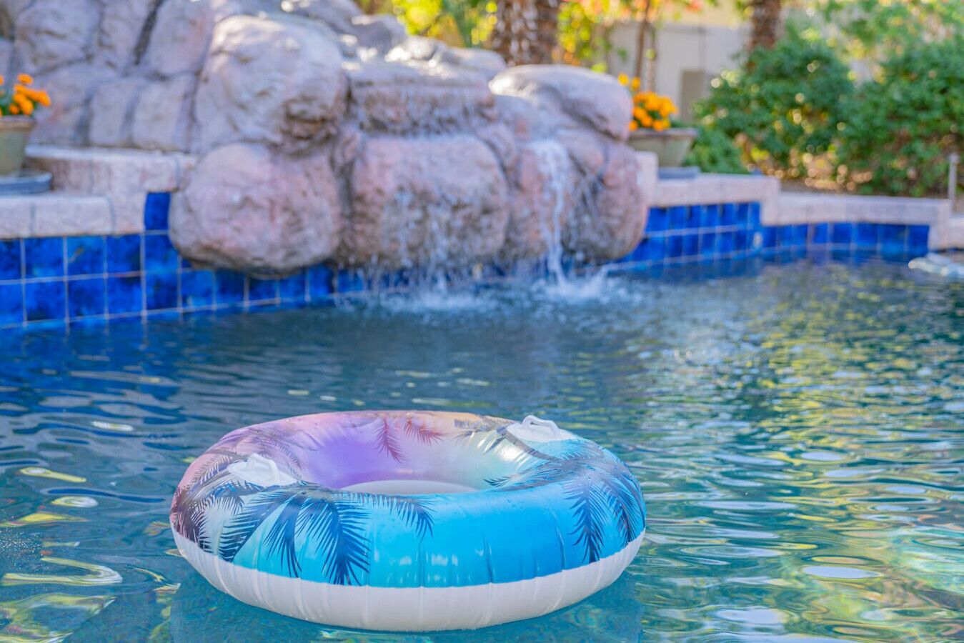 A pool with a clear water surface, a floating ring, and a rock waterfall feature.