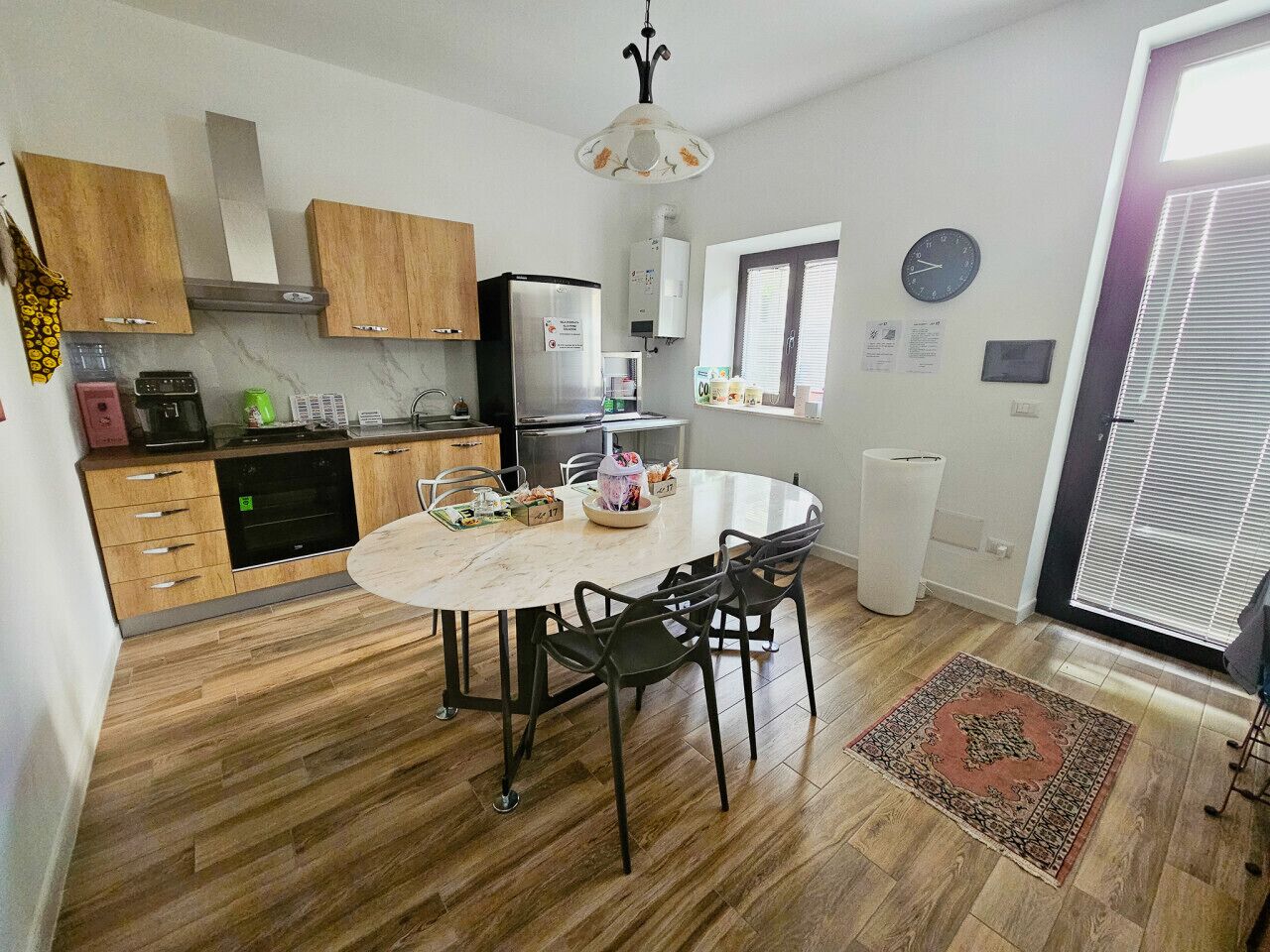 A kitchen with wooden cabinets, a white dining table with chairs, a built-in oven, and a water heater.