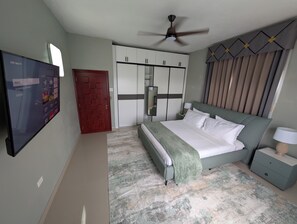 Un dormitorio con cama, mesita de noche, armario y ventilador de techo.