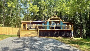 A wooden cabin with a deck, surrounded by trees. - New cottage with Hot Tub, Tiki Bar, Sauna, and Plunge Tub. Million Dollar Views (Brevard)