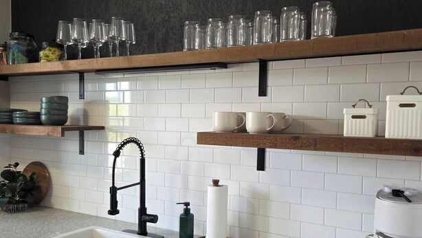 A kitchen with a white sink, black cabinets, and a speckled countertop. There are shelves above the countertop holding glasses and jars. - The Washington Suite on the main street in Downtown Cedarburg (Cedarburg)