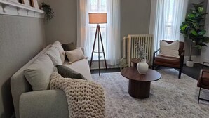 A living room with a sofa, a coffee table, a lamp, a radiator, and a chair. - The Washington Suite on the main street in Downtown Cedarburg (Cedarburg)