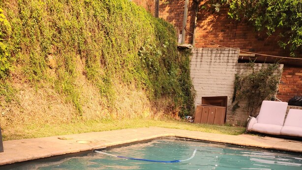 Una piscina con agua cristalina, una manguera azul y una persona de pie en el agua.