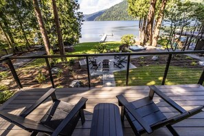 A deck with outdoor seating overlooking a lake and mountains.