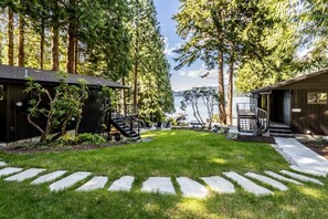 A cabin with a deck, a stone pathway, and a view of the lake.