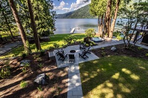 Un patio con mobiliario exterior, una bañera de hidromasaje y vistas a un lago y montañas.
