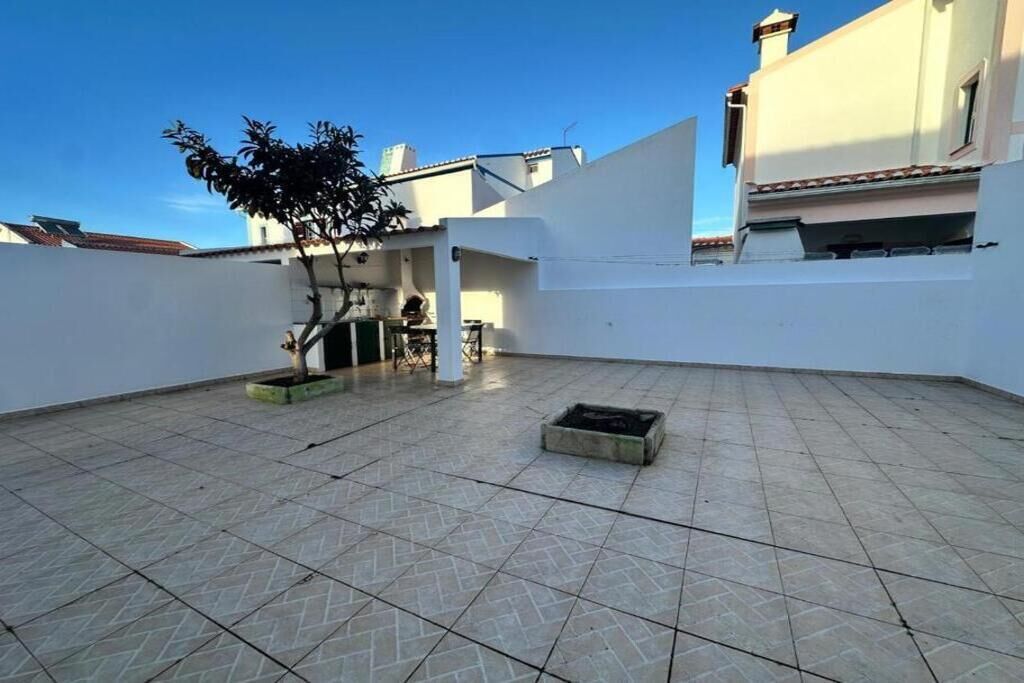 Une terrasse sur le toit, dotée d’un sol carrelé, d’un petit arbre et d’un bac à fleurs en béton.