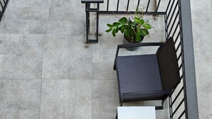 A rooftop terrace with a seating area consisting of a table and two chairs, a potted plant, and a flower arrangement.