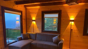 A cozy room with a sectional sofa, two windows with blinds, and wall-mounted lights. - Of Kartepe Bungalov & İkiz Villalar (Of)