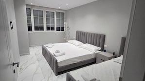 A modern bedroom with two beds, a large window, and a marble floor. - Prestige Beach Apartament Durres (Durres)
