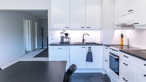 A modern kitchen with white cabinets, a black countertop, a coffee maker, and a sink.