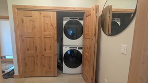 Une buanderie équipée de deux lave-linge Whirlpool superposés et dotée d’une porte en bois.