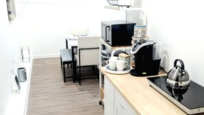 A modern kitchen with a wooden countertop, a kettle, a coffee maker, and a microwave.