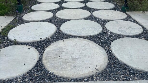 A pathway with circular stepping stones leading to modern buildings with balconies and palm trees. - The Windown Suite Near Downtown Punta Cana (Higuey)
